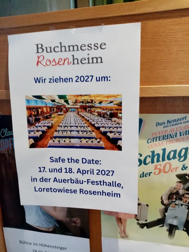 Ein Plakat mit der Ankündigung, dass die Buchmesse Rosenheim nächstes Jahr in der Auerbräu-Festhalle stattfinden wird. Am 17. und 18. April 2027